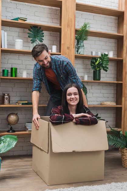 Free photo cheerful man dragging box with woman