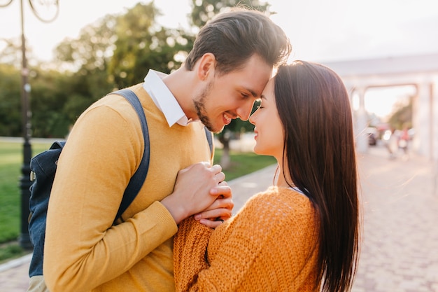 Cheerful man looking at dark-haired woman with tenderness in good autumn day