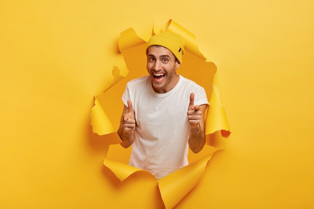 Cheerful man makes finger gun gesture directly at camera, expresses choice