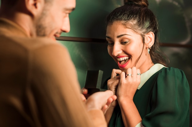 Free photo cheerful man presenting gift in box to young surprised woman