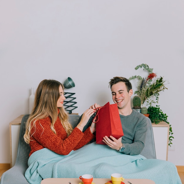 Cheerful man receiving gift from woman