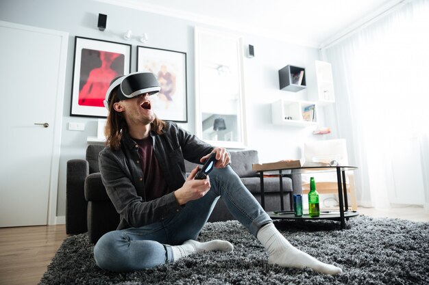 Cheerful man sitting at home indoors play games