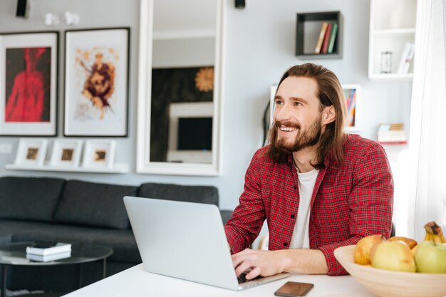 Cheerful man sitting in the table using laptop at home