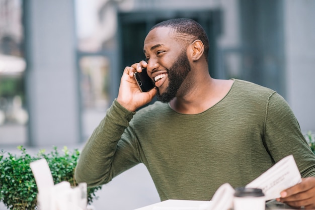 Cheerful man speaking on phone in cafe