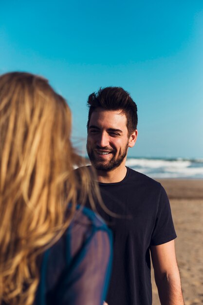 Cheerful man speaking with woman on beach