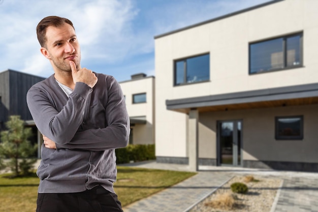 Free photo cheerful man standing in front of new house.