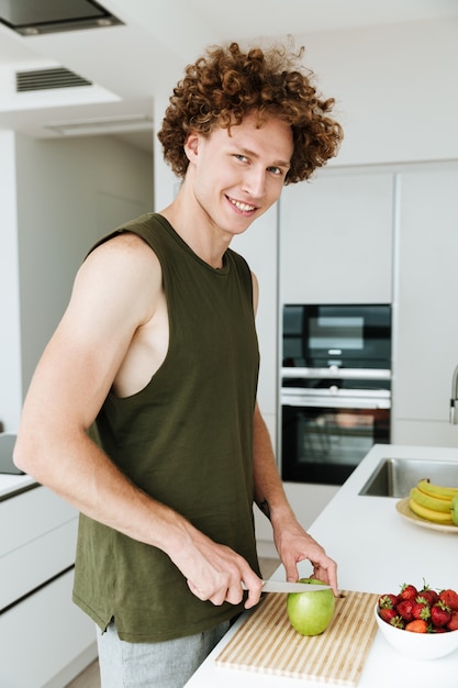Cheerful man standing at the kitchen and cooking