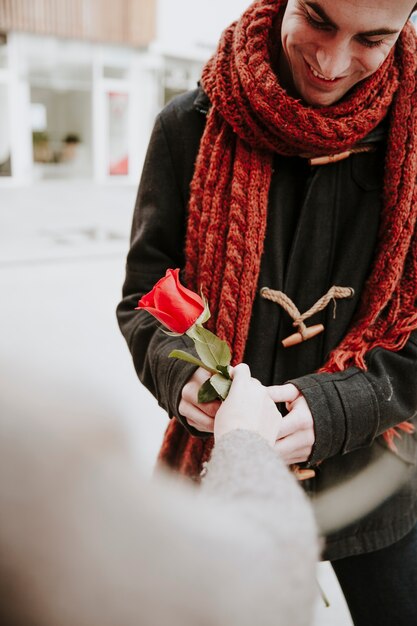 Cheerful man taking rose from woman