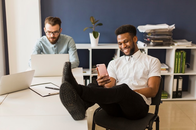 Cheerful man using smartphone in office