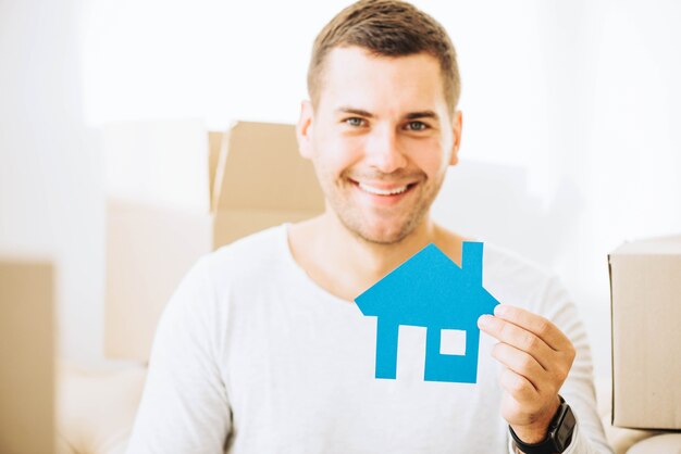 Cheerful man with blue house in hands