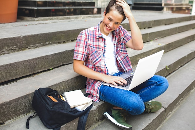 Free photo cheerful man with laptop on stairs