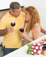 Foto gratuita allegra coppia matura che trascorre la giornata a casa uomo e donna sorridenti e in possesso di bicchieri con delizioso vino rosso