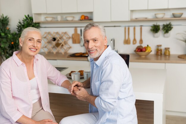 Cheerful mature loving couple family sitting at the kitchen