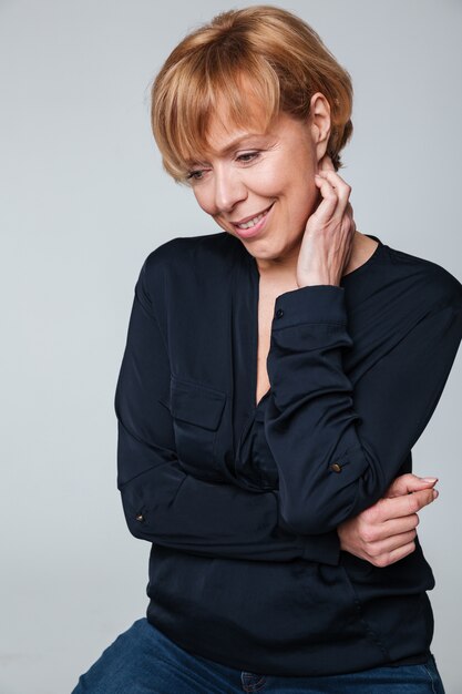 Cheerful mature woman sitting and posing isolated