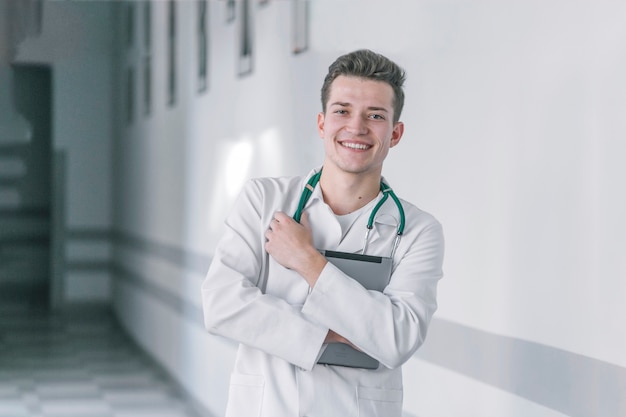 Cheerful medic with tablet in hallway