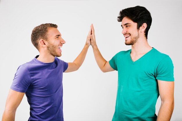 Cheerful men in bright t-shirts giving high five