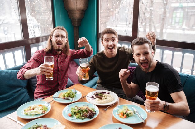 ビールを飲みながらカフェに座っている陽気な男性の友人。