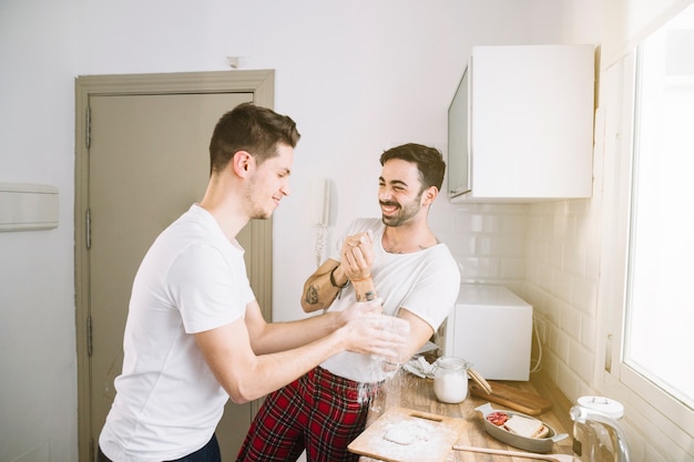 Free photo cheerful men playing while making breakfast