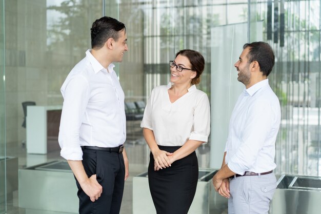 Cheerful mid adult businesswoman in glasses talking to partners