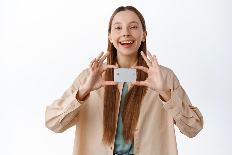 Free Photo cheerful millennial girl shows her credit card and smiles pleased recommend new bank feature banking offer standing over white background