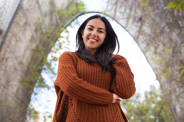 Foto gratuita ragazza allegra della corsa mista in maglione che cammina nel parco