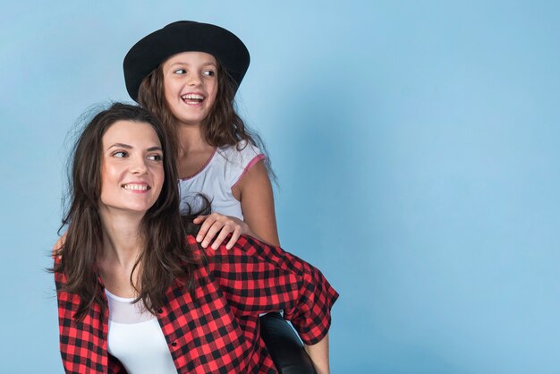 Cheerful mother carrying daughter on back