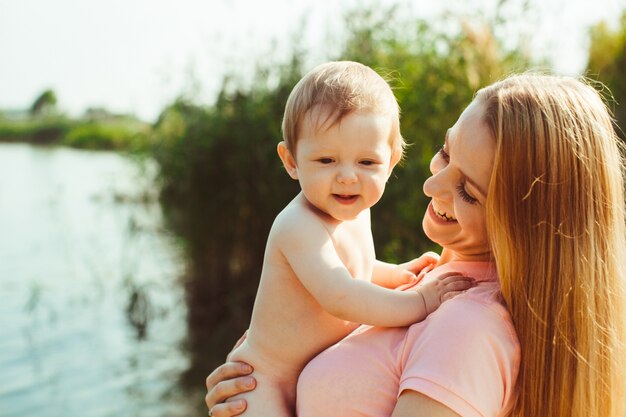 Cheerful mother holds naked baby in her arms