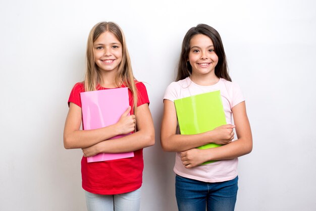 Cheerful multiethnic schoolgirls with workbooks