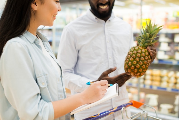 Cheerful multiethnical couple buying goods in supermarket