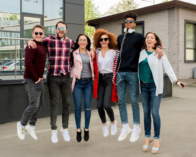 Cheerful multiracial group of people jumping together on street