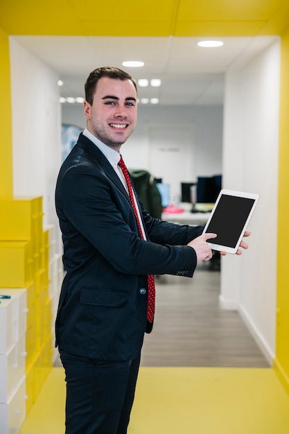 Cheerful office man pointing at tablet in hands