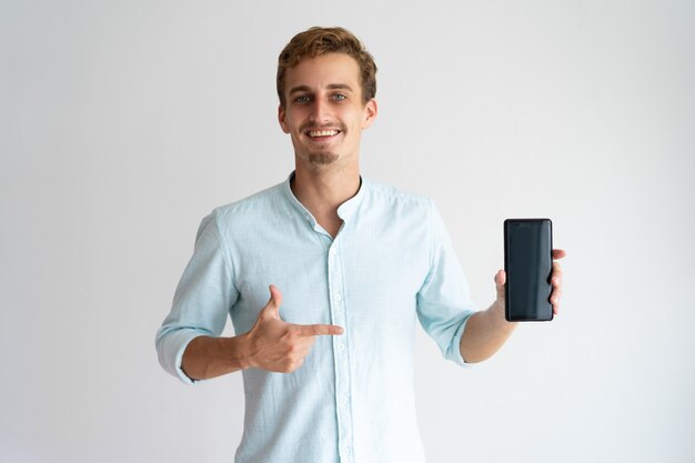 Веселый оптимистичный менеджер по продажам демонстрирует новый смартфон.
