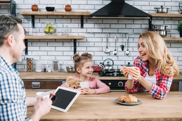 Cheerful parents and daughter enjoying breakfast in kitchen