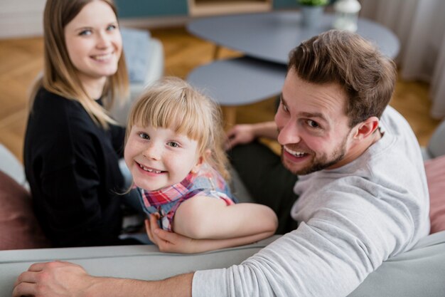 Cheerful parents and daughter looking at camera