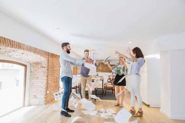 Cheerful people in office throwing papers