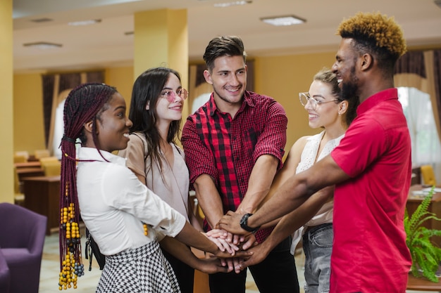 Cheerful people posing with hands stacked