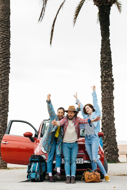 Cheerful people taking selfie near red car