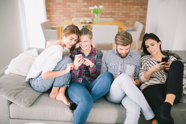 Cheerful people with gadgets on sofa