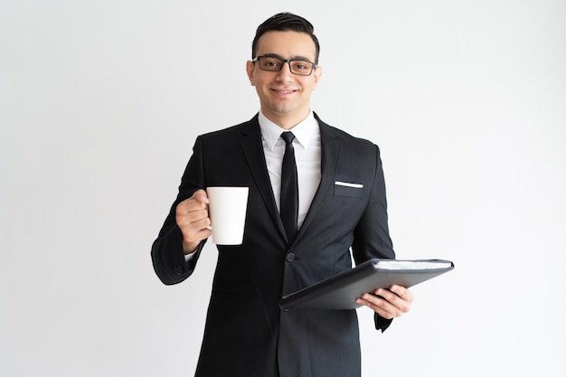 Cheerful pleased business employee drinking coffee and working with papers. 