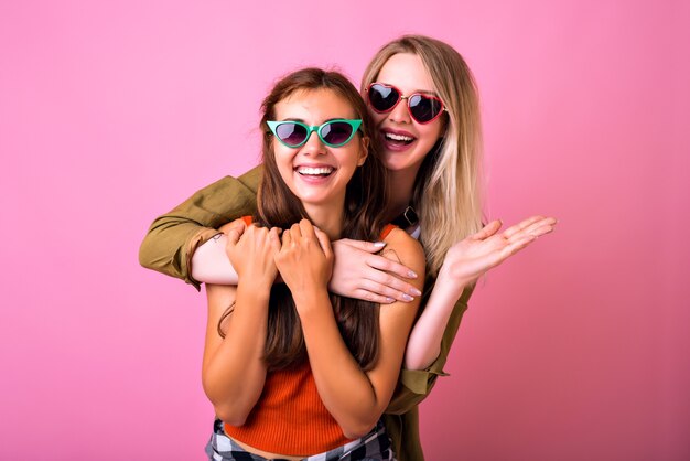 Cheerful positive indoor Portrait of two funny blonde and brunette woman hugs and looking to each other