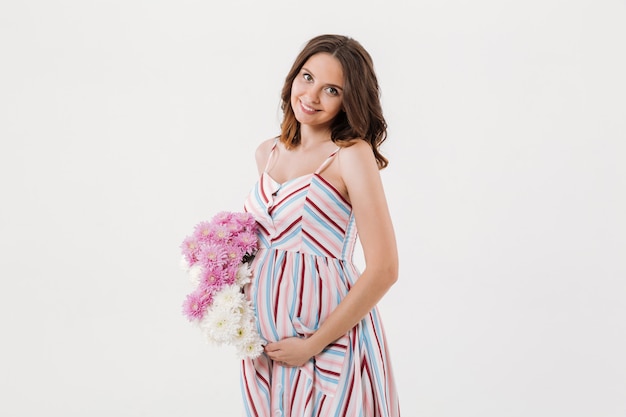 Cheerful pregnant woman holding flowers.