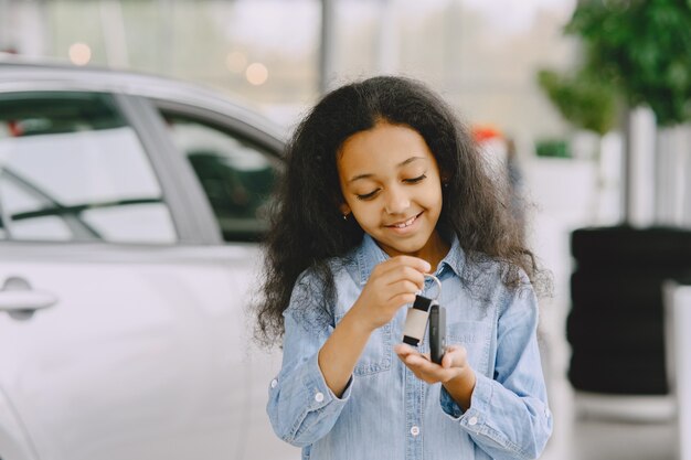 陽気でかわいい女の子、車のキーを持って、それを見せて、笑顔でポーズをとる。