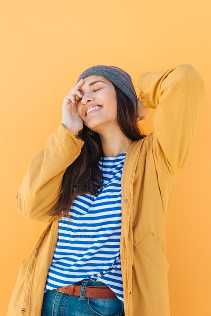 cheerful pretty woman posing wearing knit hat with her eyes closed