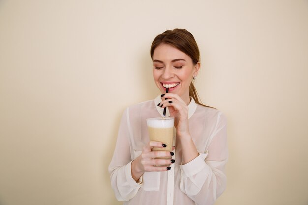 Cheerful pretty young woman drinking coffee latte and laughing