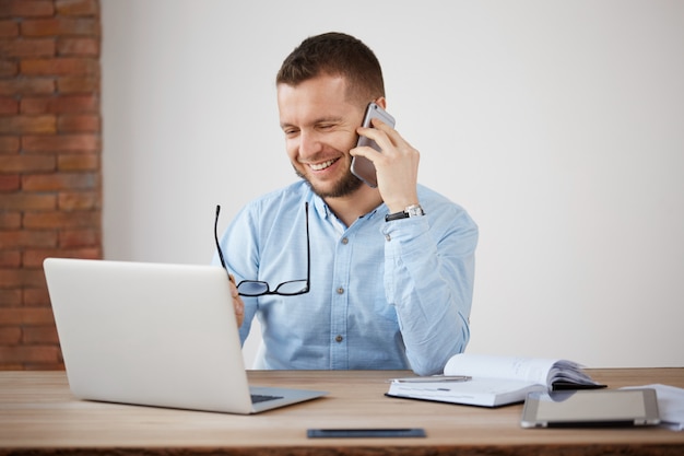 Cheerful professional shaved company director laughing, taking on glasses, looking in laptop monitor