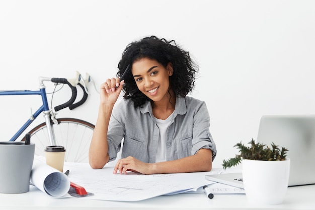 Cheerful professional young female having dark skin and curly hair wearing casual shirt