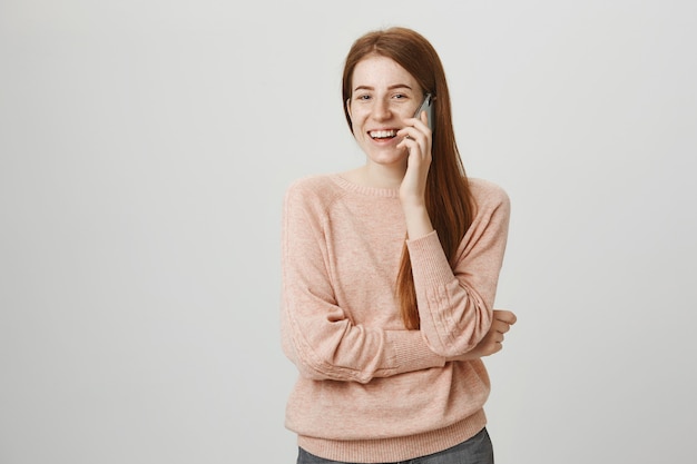 Cheerful redhead girl having mobile conversation, smiling