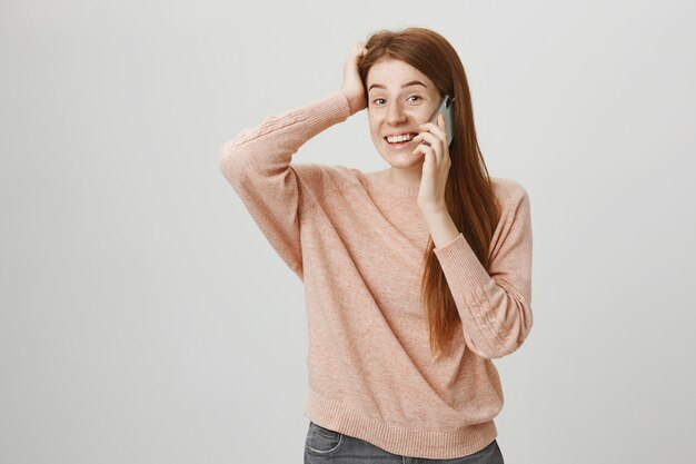 Cheerful redhead girl having mobile conversation, smiling