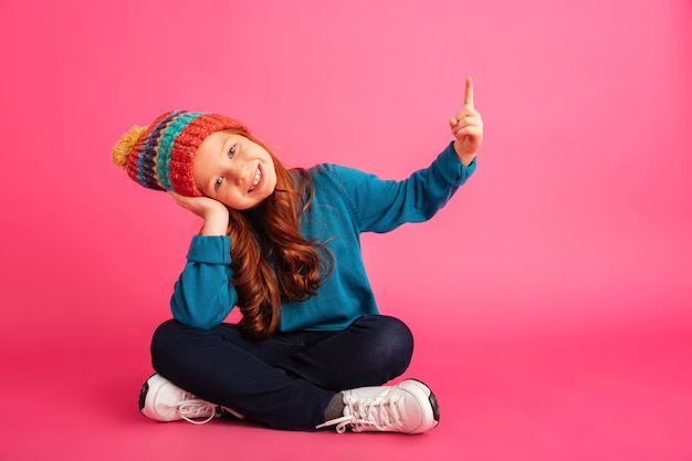 Cheerful redhead girl pointing up at copy space isolated