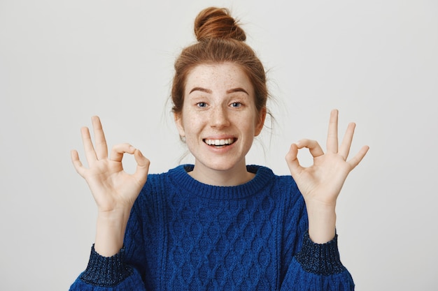 Free photo cheerful redhead girl smiling, showing okay in approval, assure everything is good